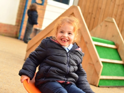 A young child playing on playground equipment with a happy face